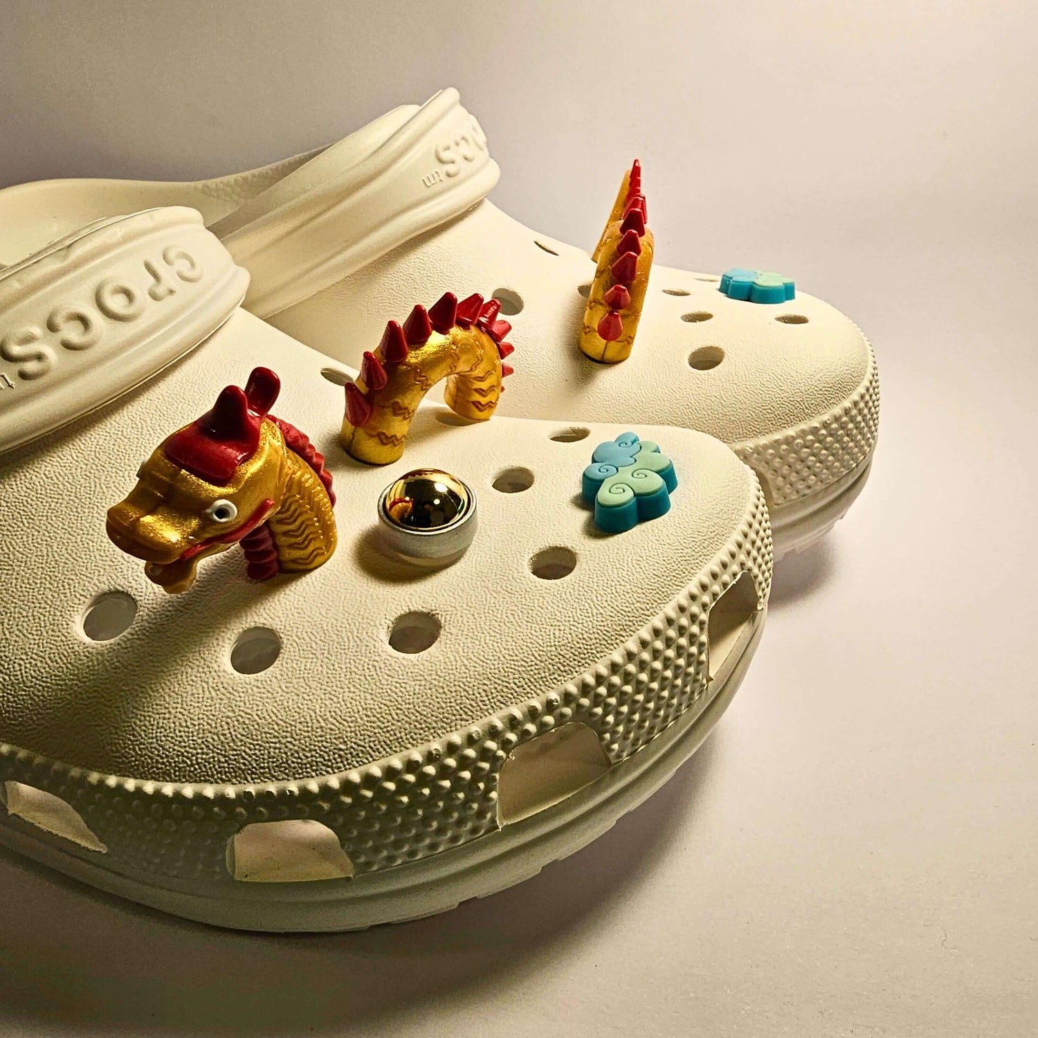 A collection of croc charms which form a flying dragon and a pearl - red and gold