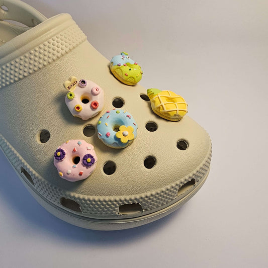 A group of jibbitz featuring realistic donut charms on a croc